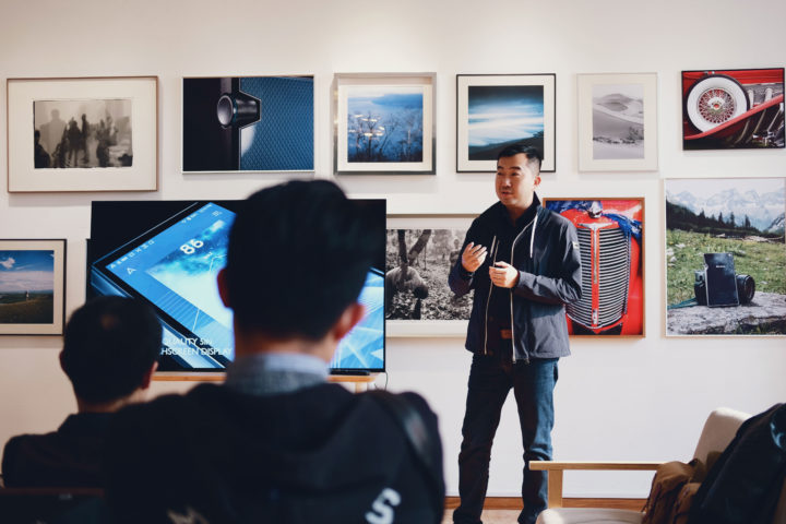 art teacher lecturing students in front of a gallery wall