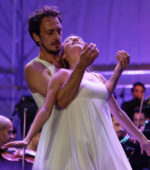 two classical dancers dancing in front of an orchestra