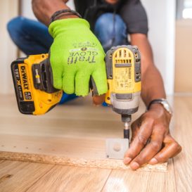 worker holds a drill to a piece of wood