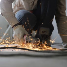 sparks fly as from a drill being held by a worker