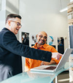 two colleagues review presentation on a laptop
