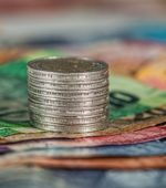 stack of coins sits atop colorful money