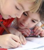 two young kindergarteners work on writing letters