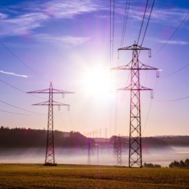 power lines stretching across a field against a blue sky