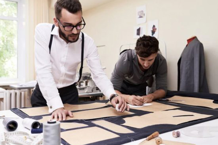 fabric and apparel patternmakers working on arranging clothing patterns on fabric