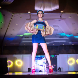 runway model on the catwalk wearing a blue and tan dress in bright pink heels