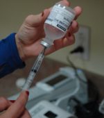 nurse prepares medication from glass bottle