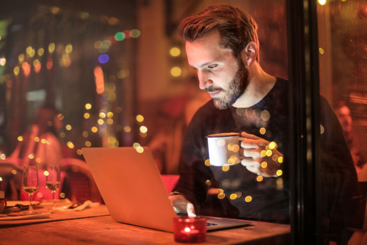 Restaurant and Food Service Manager sits in restaurant at night working on laptop