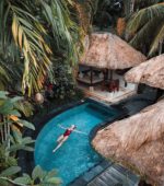 woman floating on her back in a small pool at a tropical resort