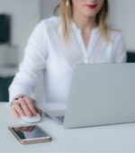 lady in white blouse working on a mac laptop