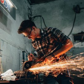 iron worker holds tool as sparks flu