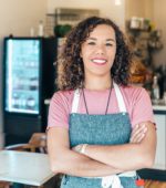 barista stands in front of coffee shop