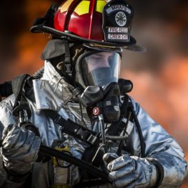 fire fighter stands in front of burning building