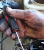 dirty hand holding small screwdriver
